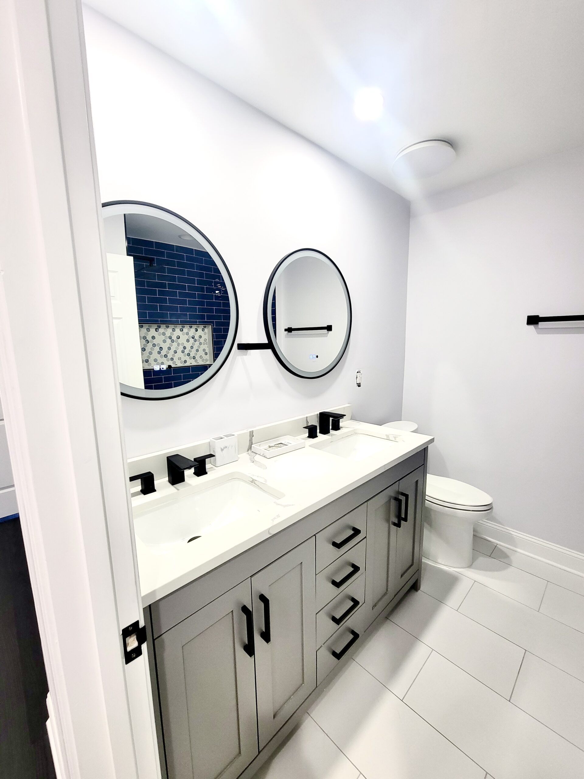 Gray vanity bathroom remodel in Accokeek Maryland with round LED mirrors.