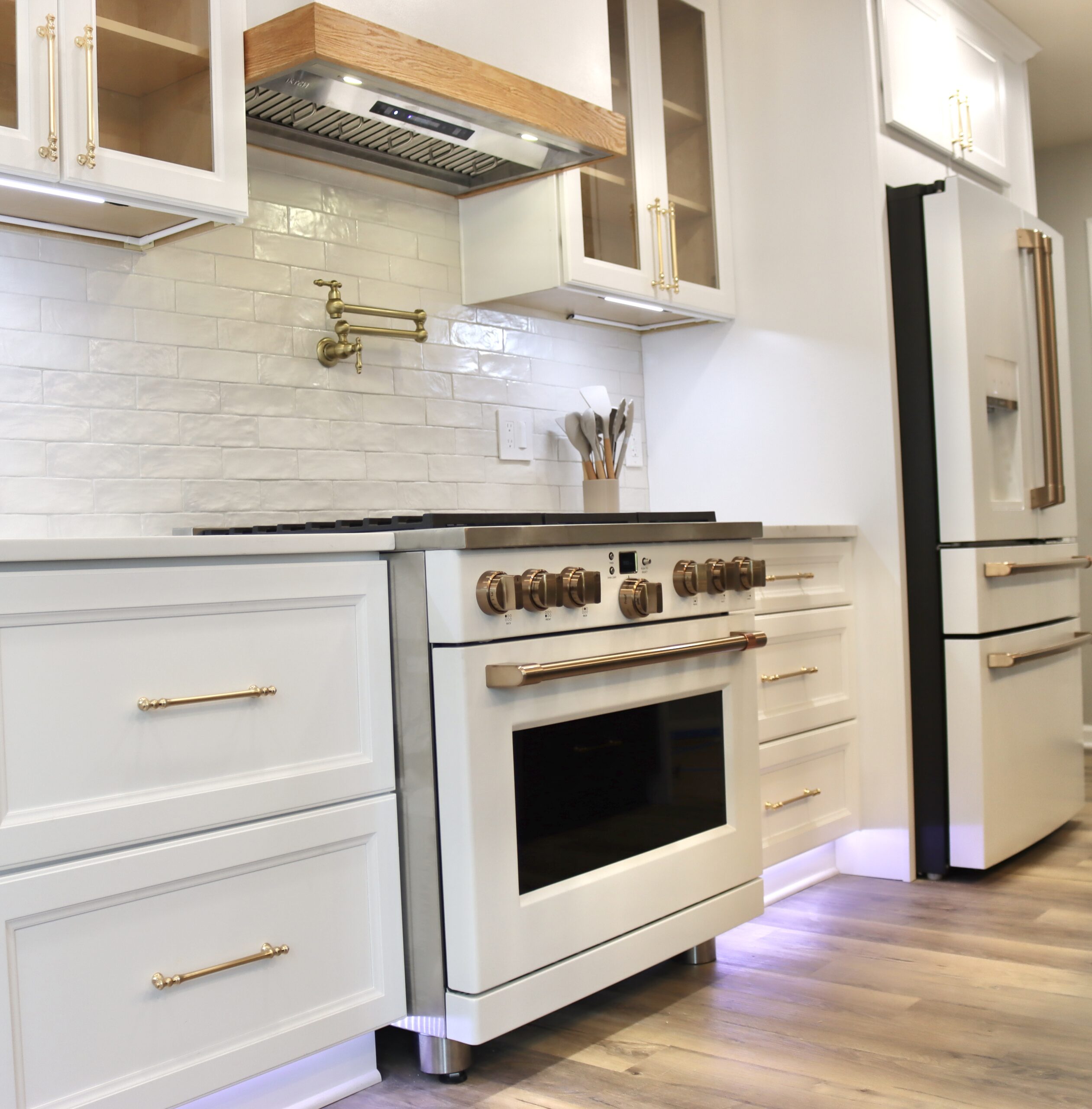 Wood range hood with gold pot filler and statement tile detail in Accokeek, MD