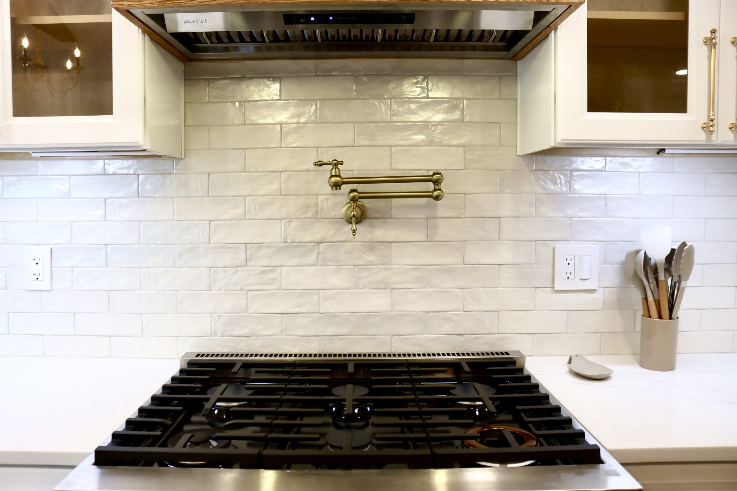 Gold pot filler and wood hood over gas range with subway tile backsplash in Accokeek, MD