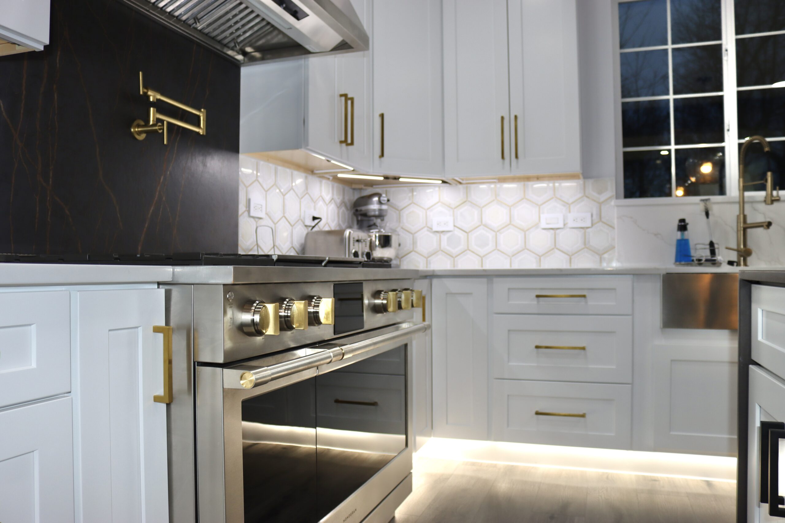 Under-cabinet LED lighting with gold pot filler and premium backsplash in Accokeek, MD