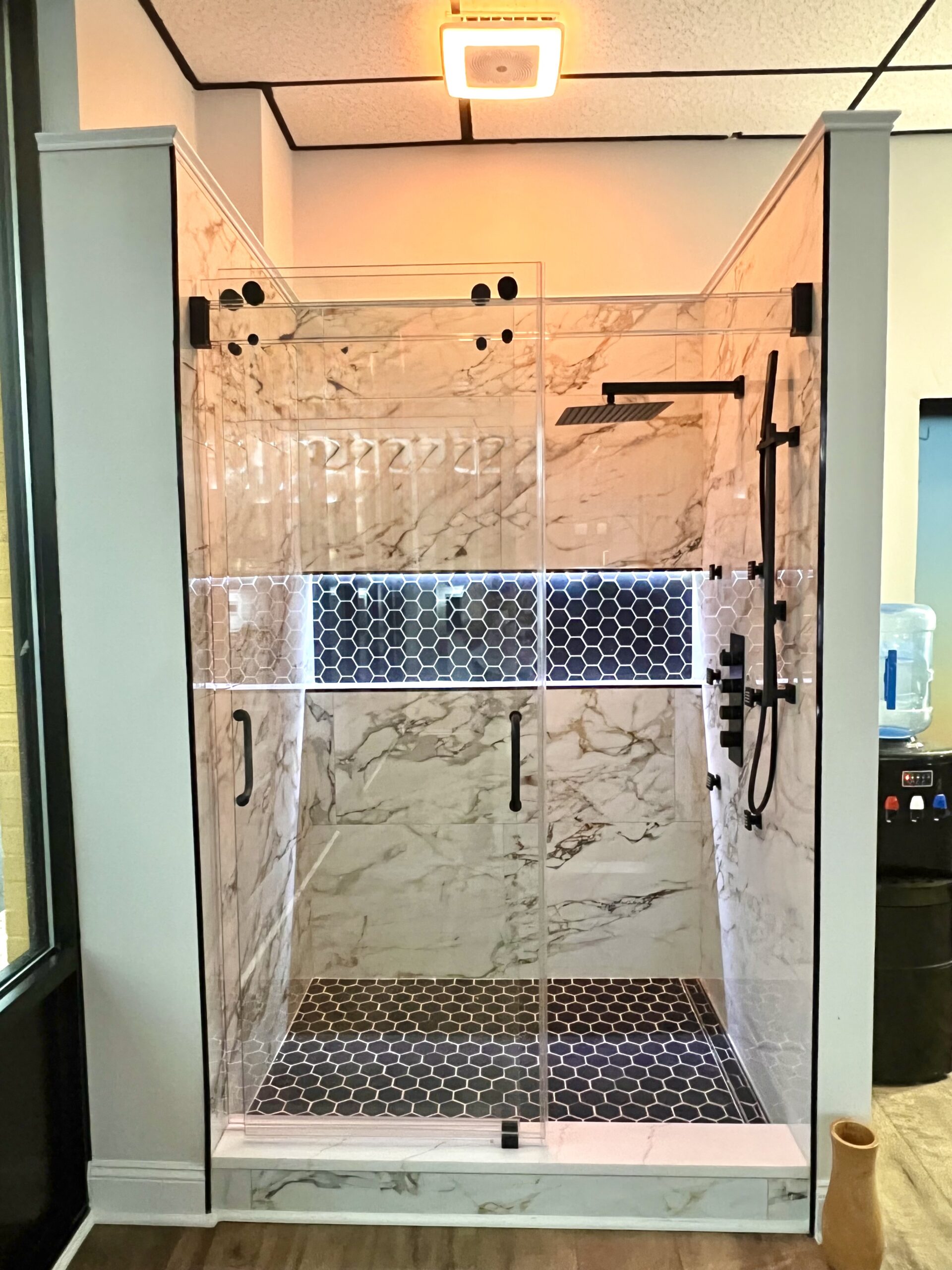 Black hex shower floor in Accokeek Maryland with marble-look walls.