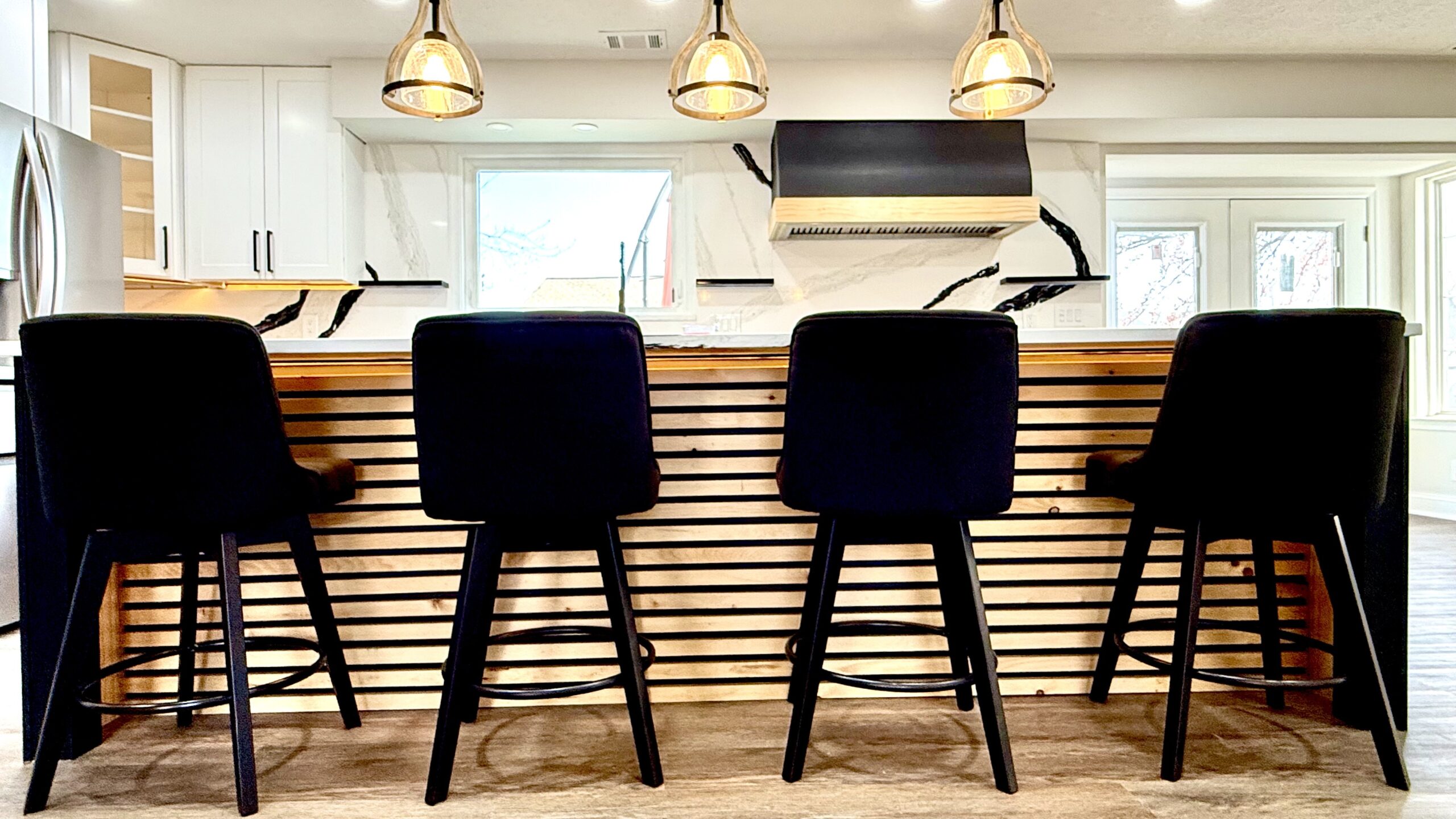 Custom slat wood kitchen island with LED lighting and black bar stools in Fort Washington Maryland by MSH Signature