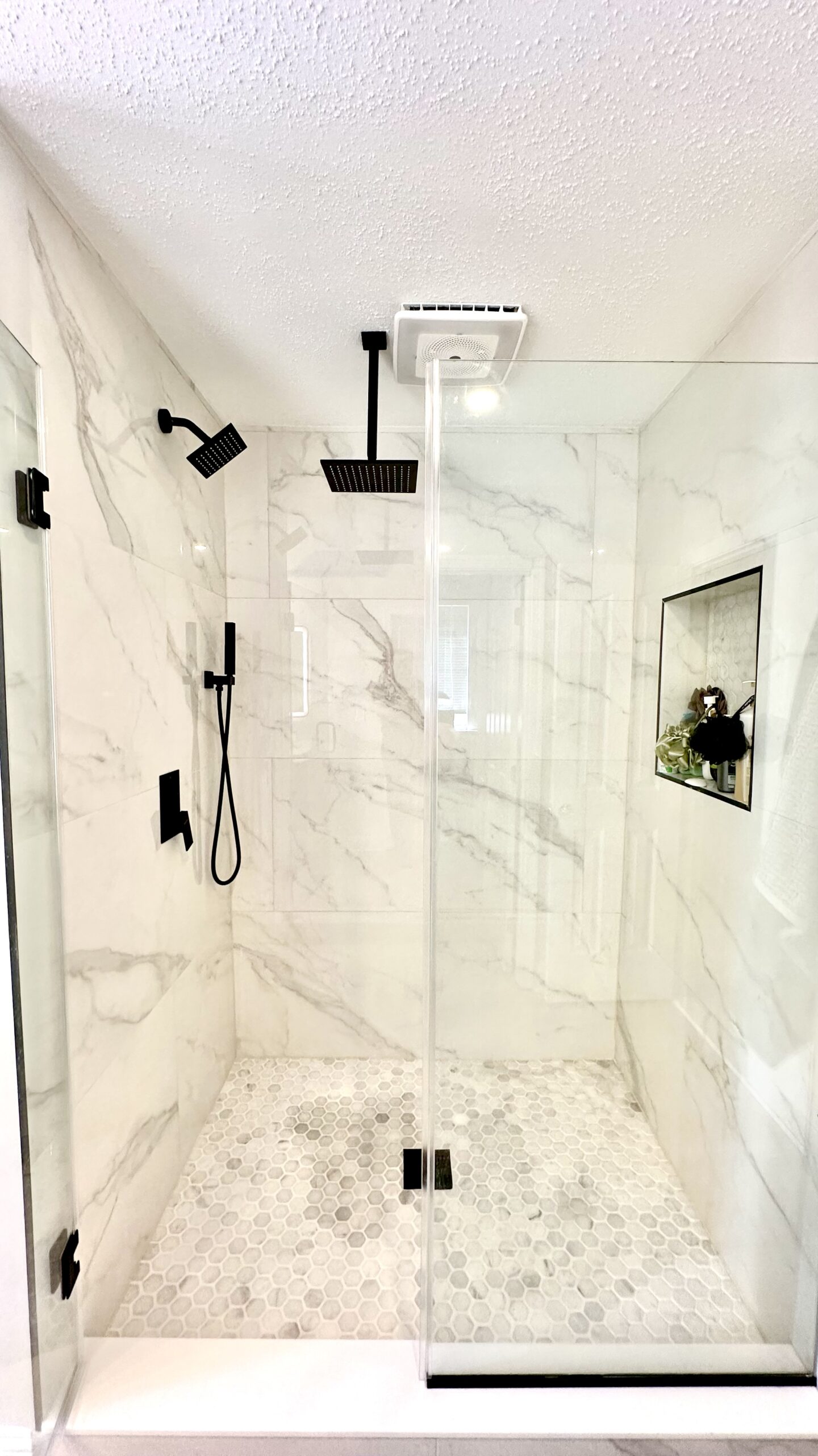 Luxury shower renovation in Brandywine Maryland with marble-look tile and matte black fixtures.